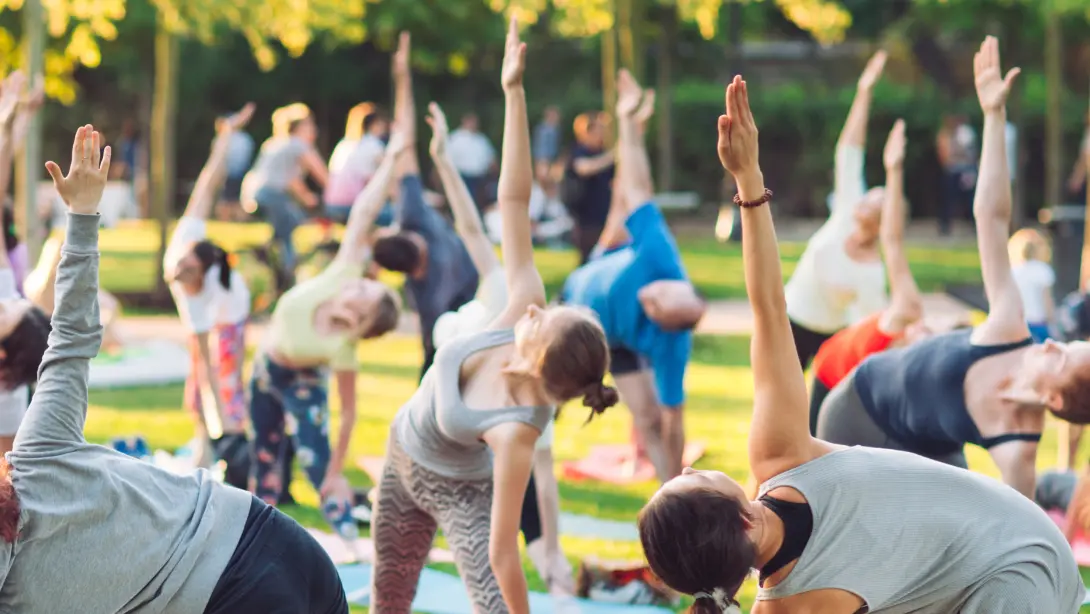 屋外で大人数でヨガをしている